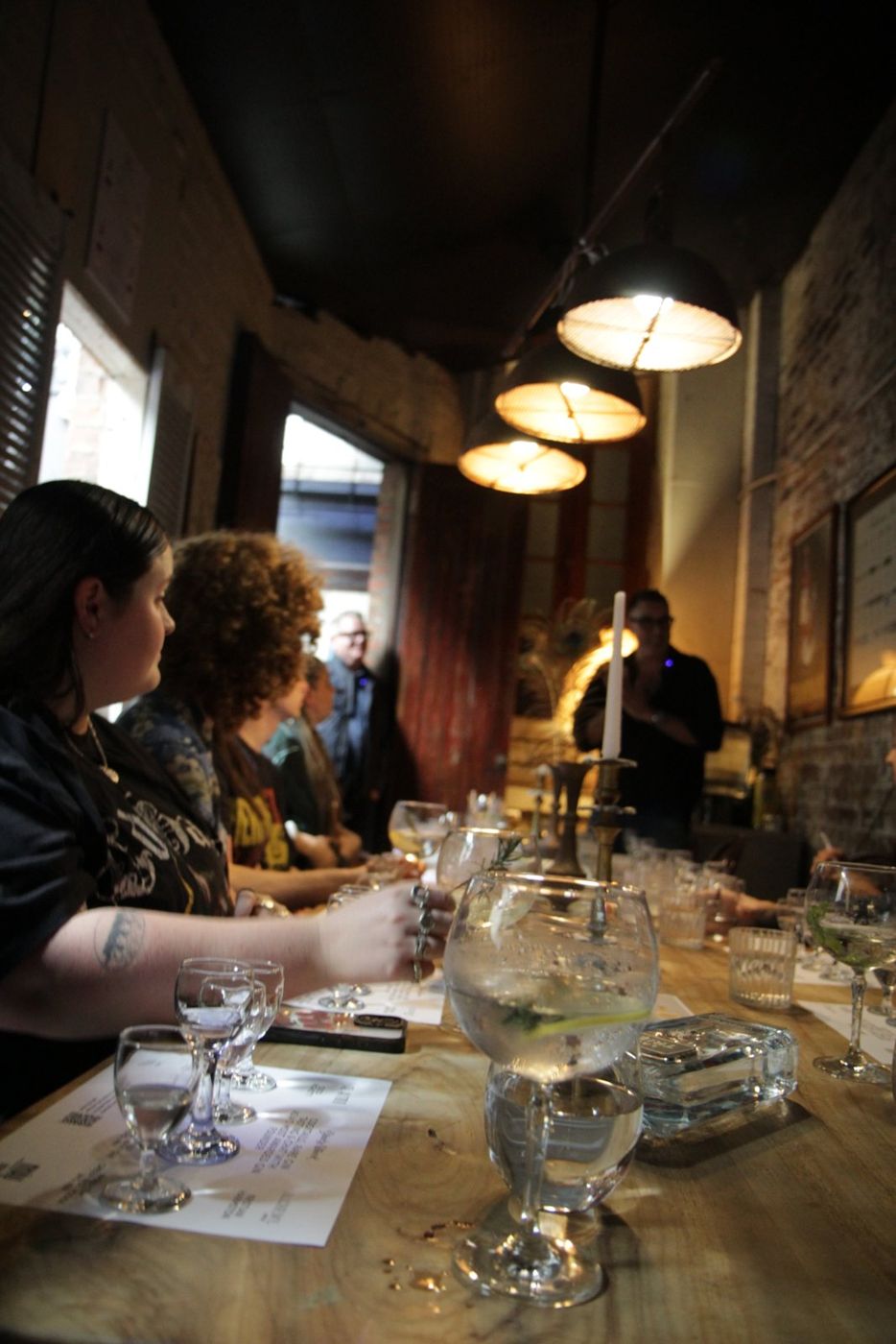 Guests at a long tasting table under pendant lights